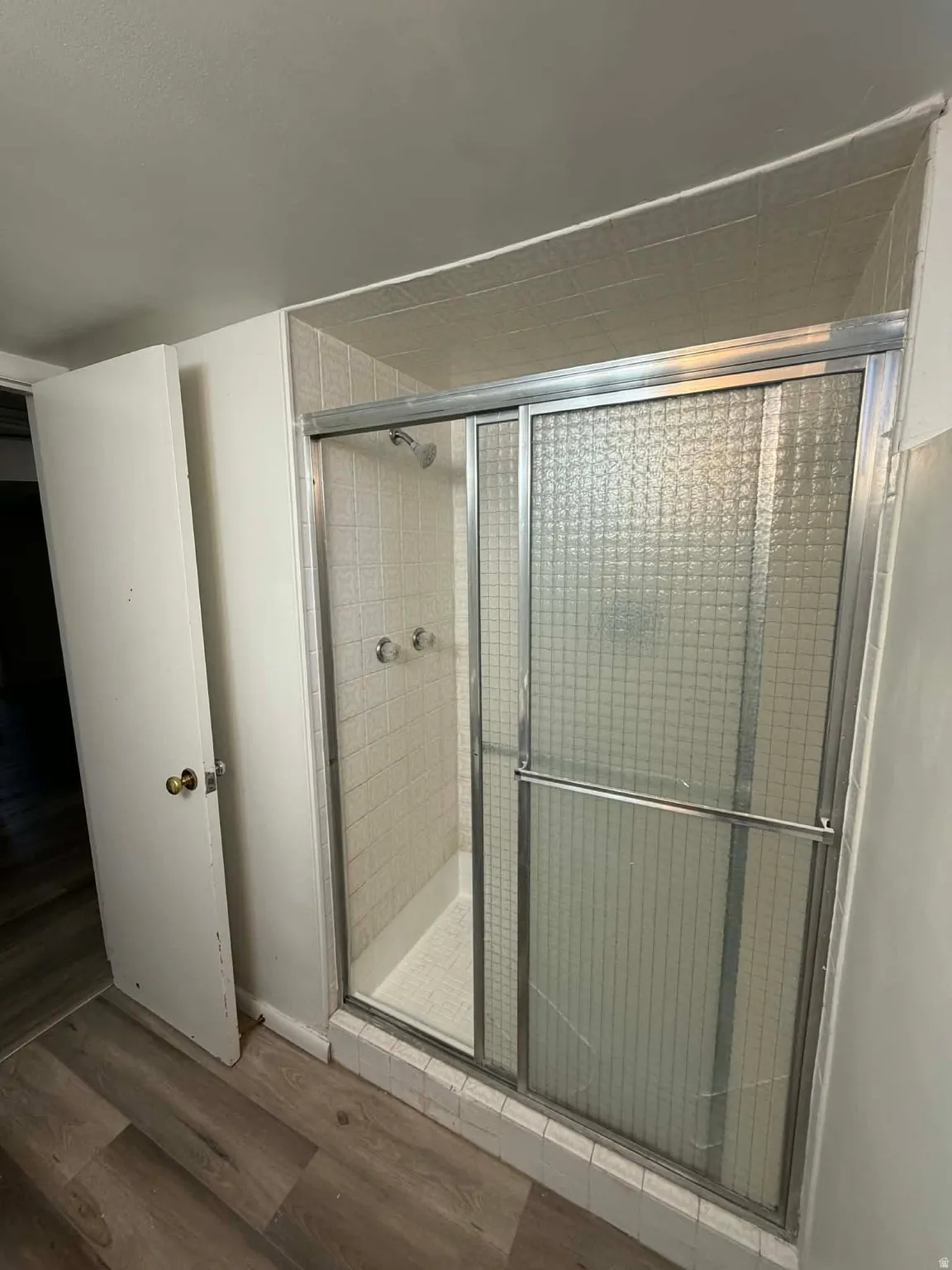 Full bath with a shower stall and wood finished floors