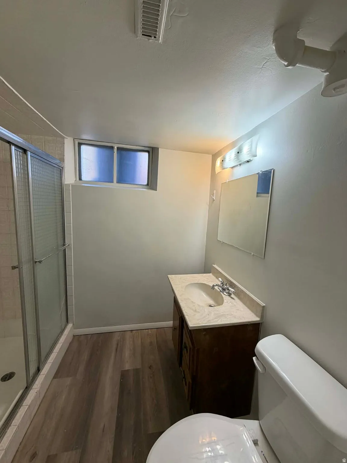 Full bathroom with a shower stall, dark wood-style flooring, and vanity
