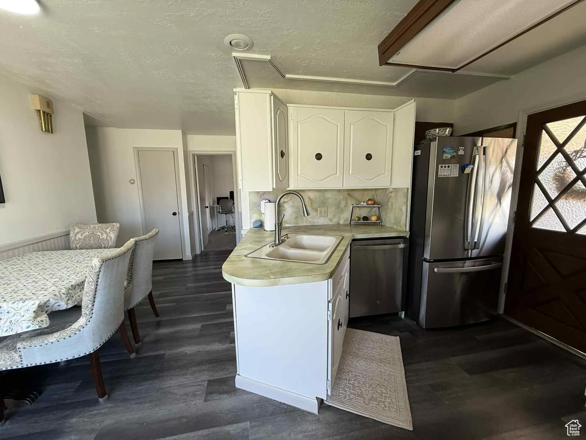 Kitchen featuring all new appliances as of 2024, white cabinetry, light countertops, appliances with stainless steel finishes, a textured ceiling, and backsplash