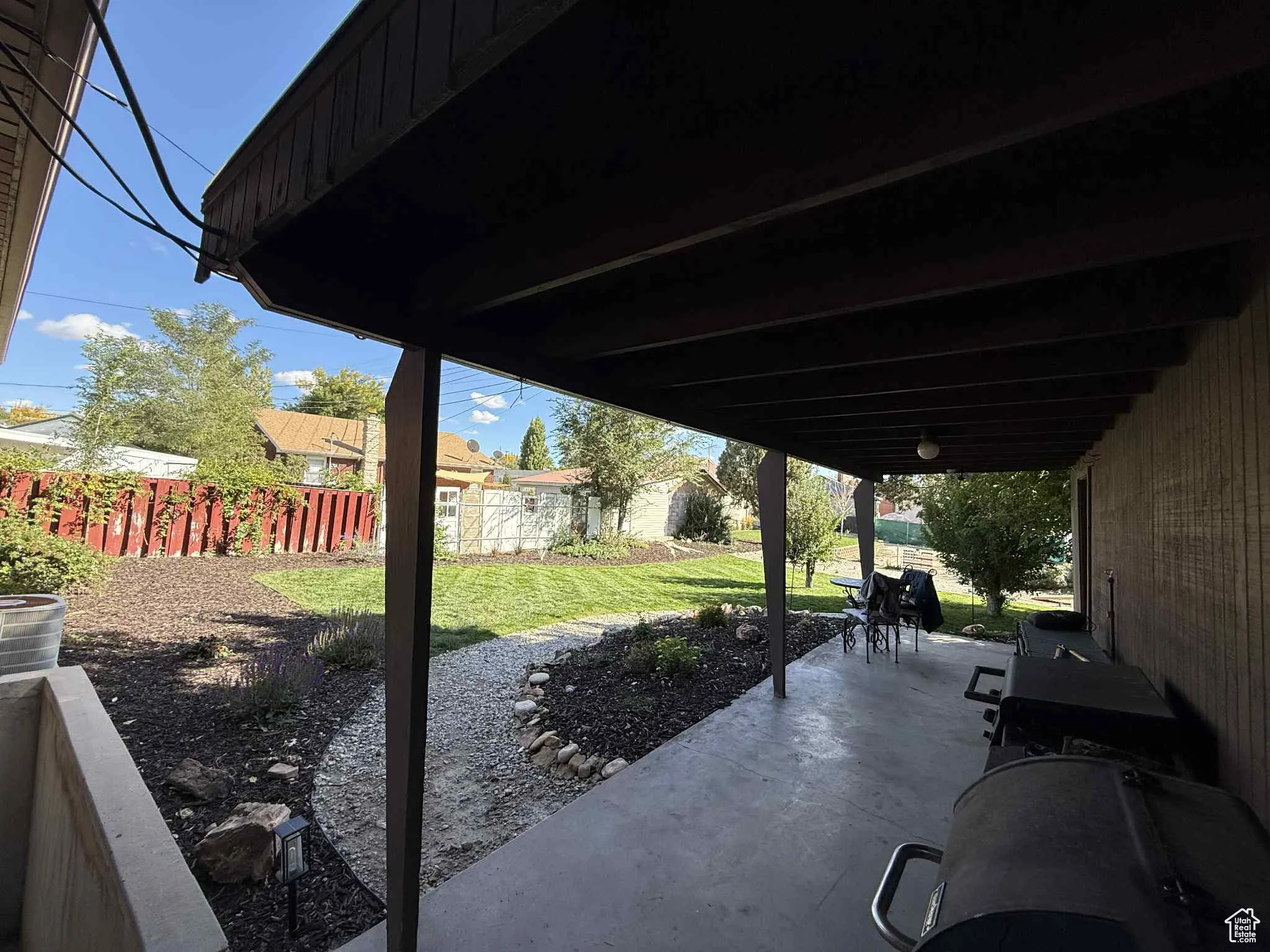 Freshly landscaped fenced backyard with a covered patio area