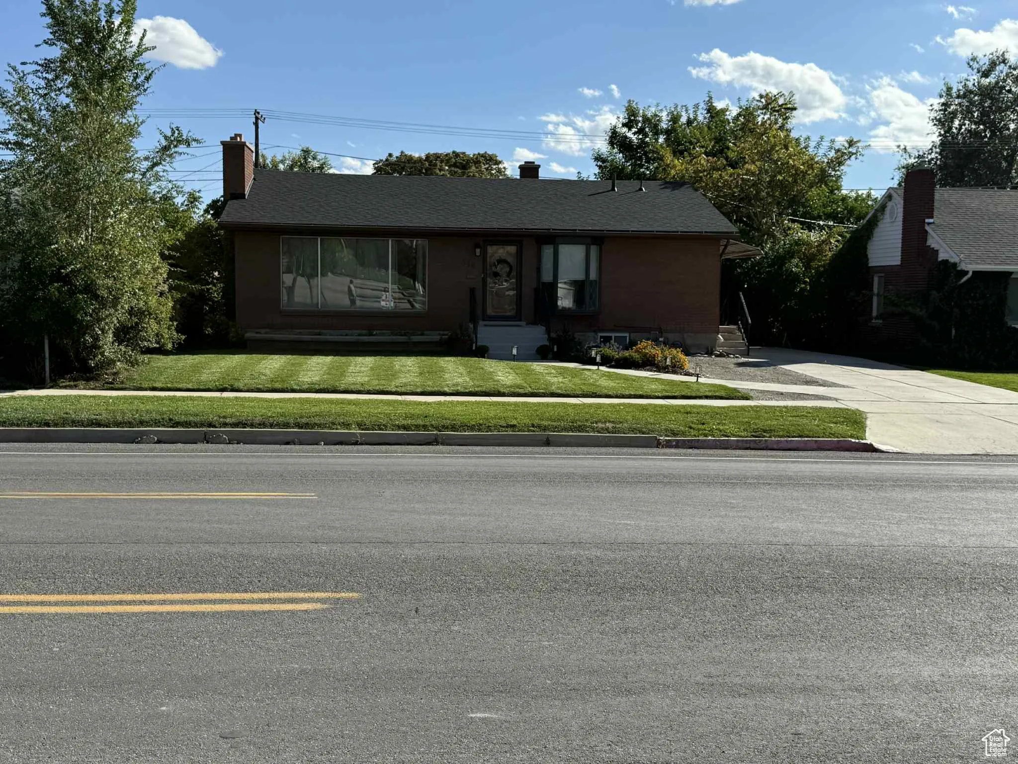 Single story home featuring a front lawn, a chimney, and concrete driveway
