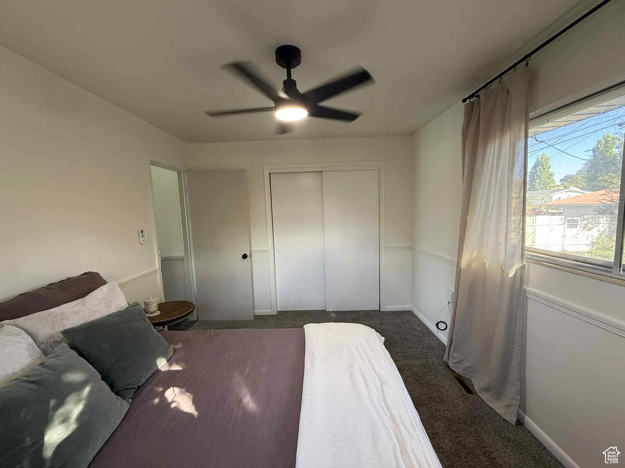 Carpeted bedroom featuring a closet and a ceiling fan