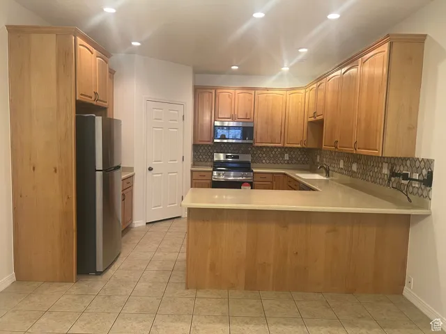 Kitchen featuring a peninsula, new stainless steel appliances ,backsplash, and recessed lighting