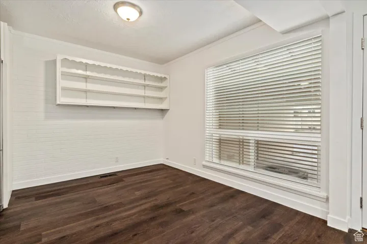 Spare room with dark wood-style floors, crown molding, and a textured ceiling