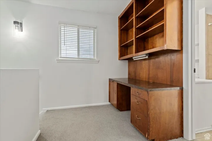 Unfurnished office featuring built in study area and light carpet
