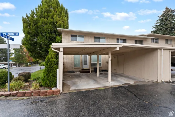 Rear view of property featuring brick siding, a patio, and an attached carport