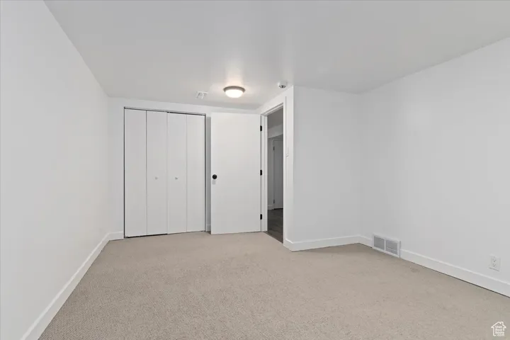 Unfurnished bedroom featuring light colored carpet and a closet