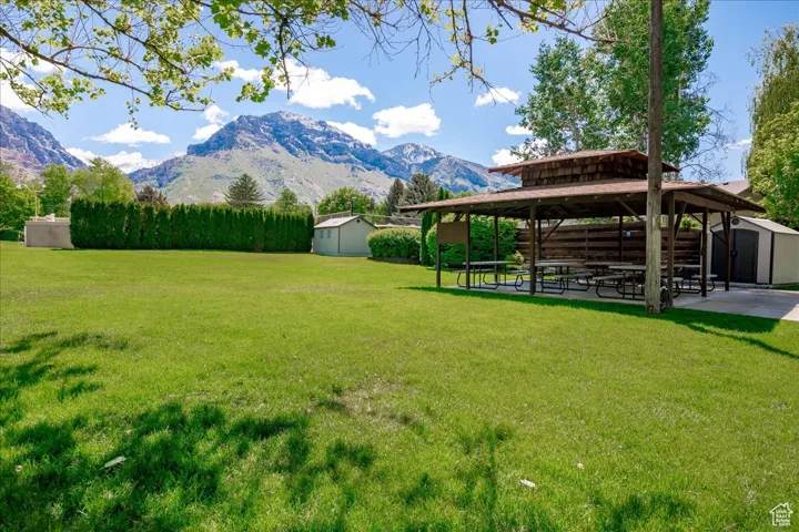 View of grassy yard with a storage shed, a gazebo, a mountain view, and a patio area