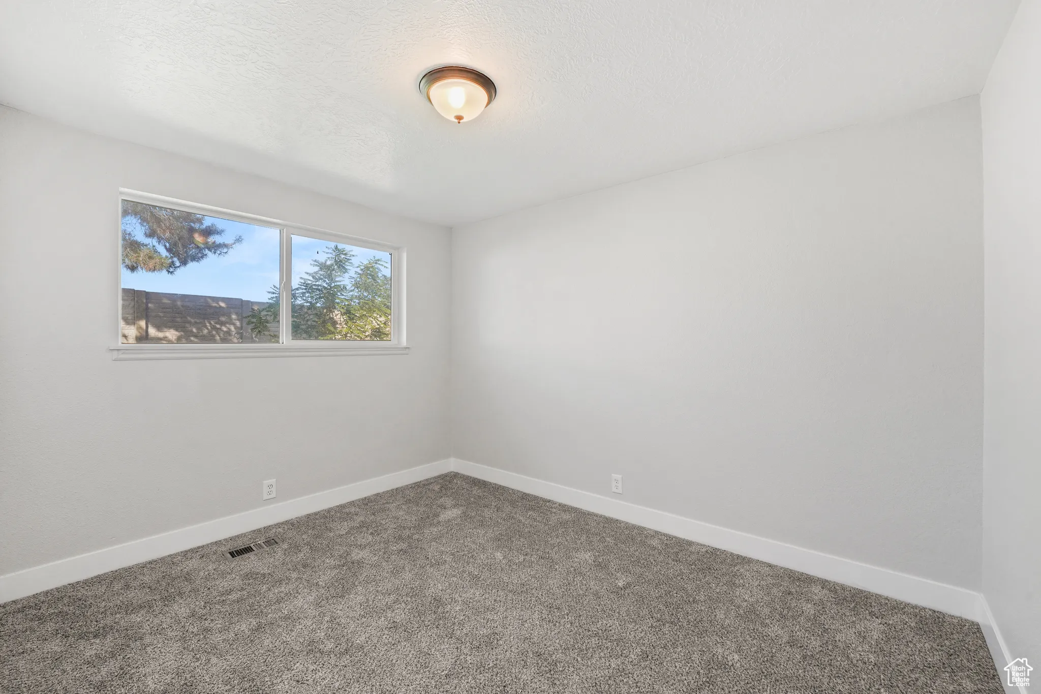 Carpeted spare room featuring baseboards and a textured ceiling