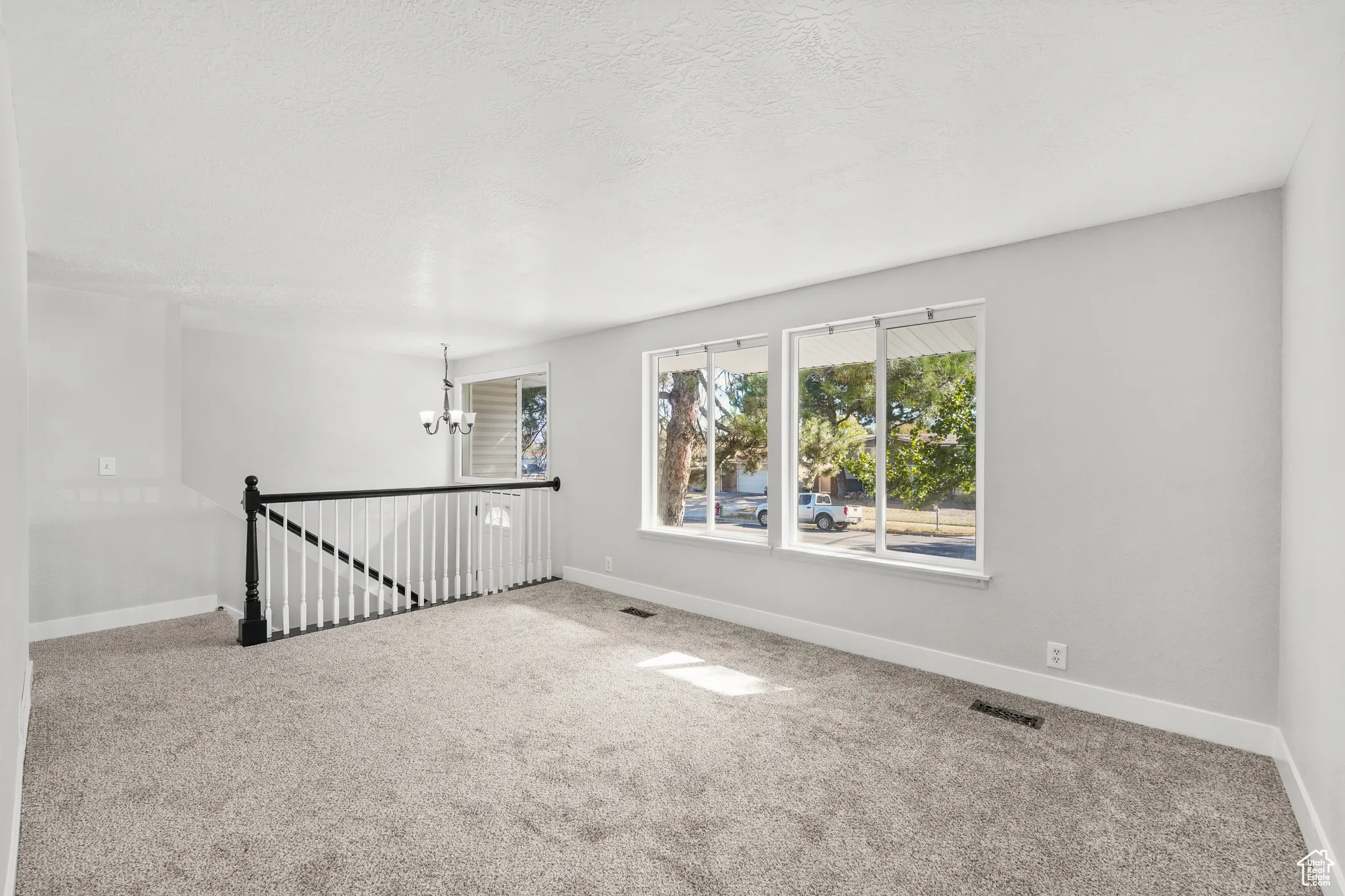 Carpeted empty room featuring a chandelier and a textured ceiling