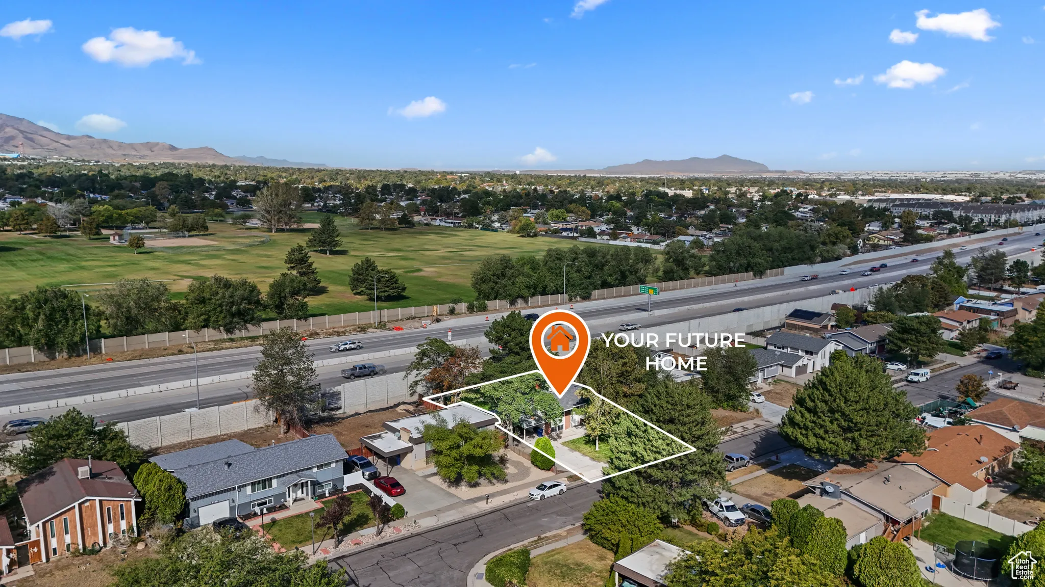 Aerial view of residential area with a mountain backdrop and property parcel outlined