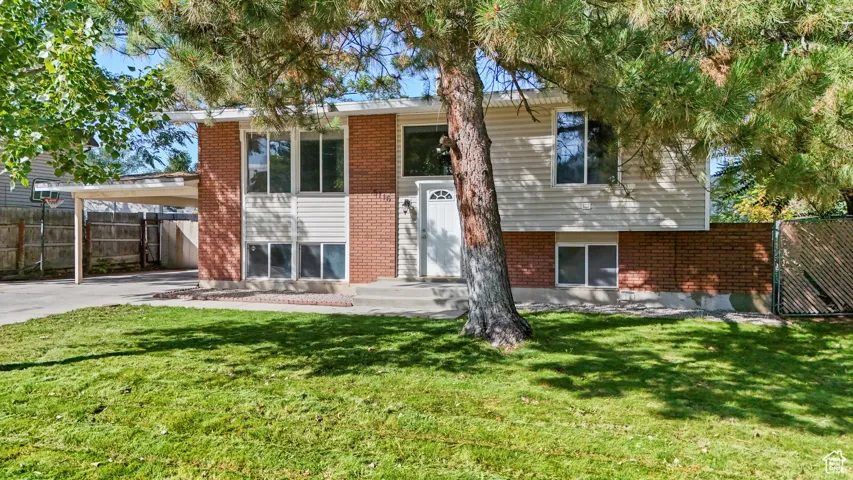 View of front of house featuring brick siding, a carport, and driveway