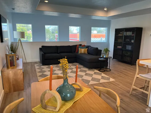 Living area featuring a tray ceiling, light wood-style floors, and recessed lighting