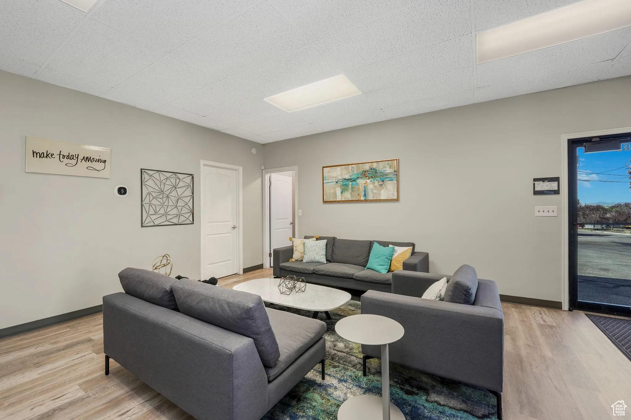 Living area featuring light wood-type flooring and a paneled ceiling