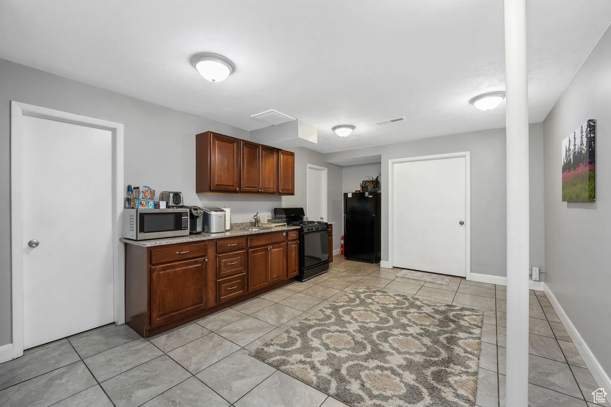 Kitchen with black appliances, light tile patterned floors, and dark stone countertops