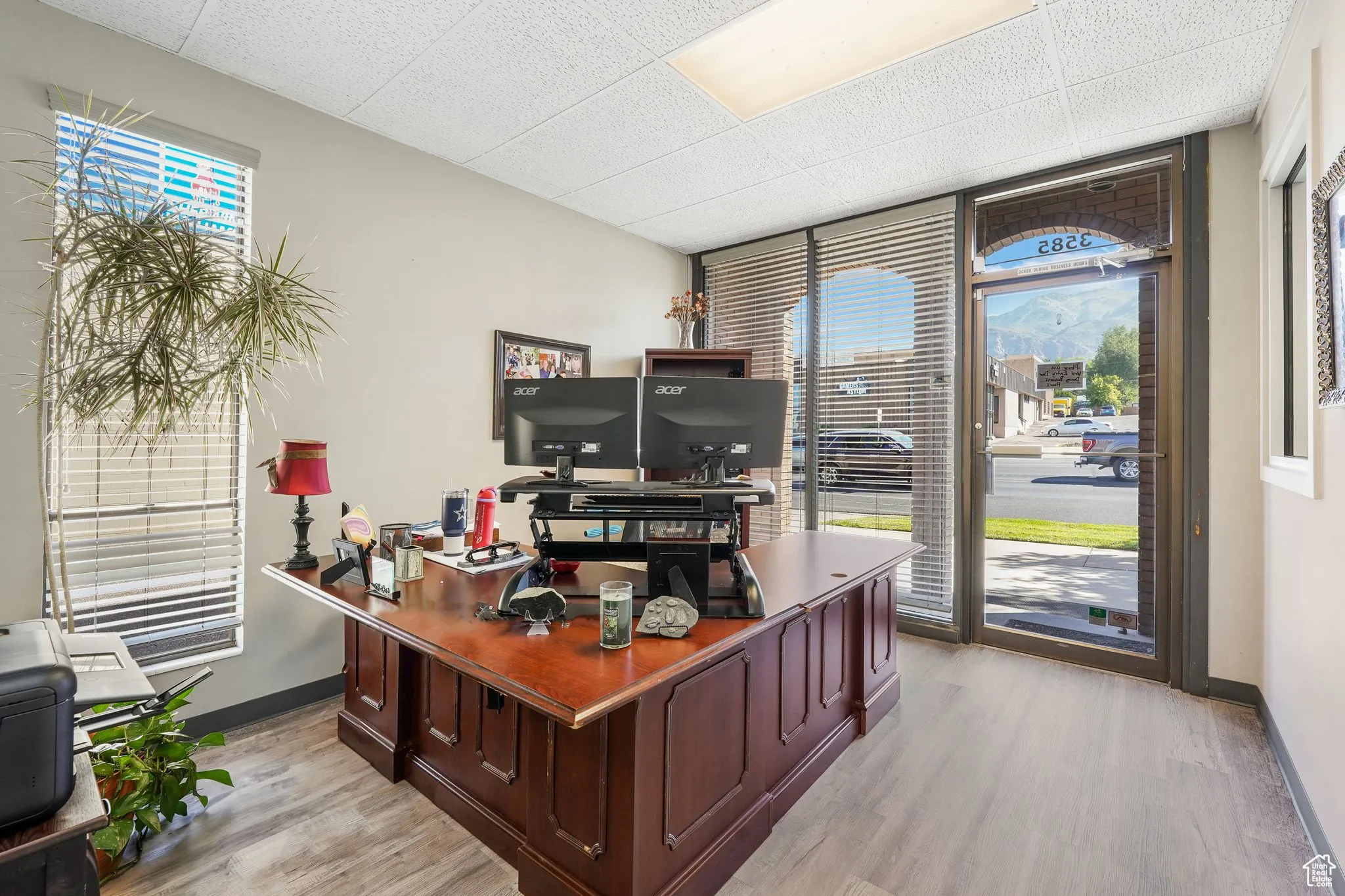Office area featuring healthy amount of natural light, expansive windows, light wood-style floors, and a paneled ceiling