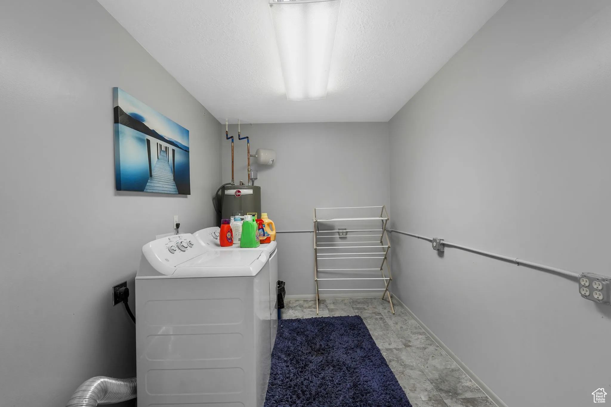 Washroom with a textured ceiling, independent washer and dryer, and water heater