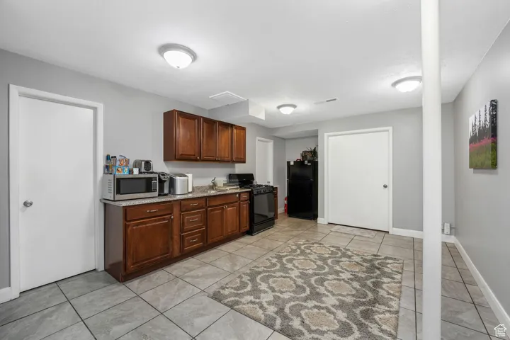 Kitchen with black appliances, light tile patterned floors, and dark stone countertops