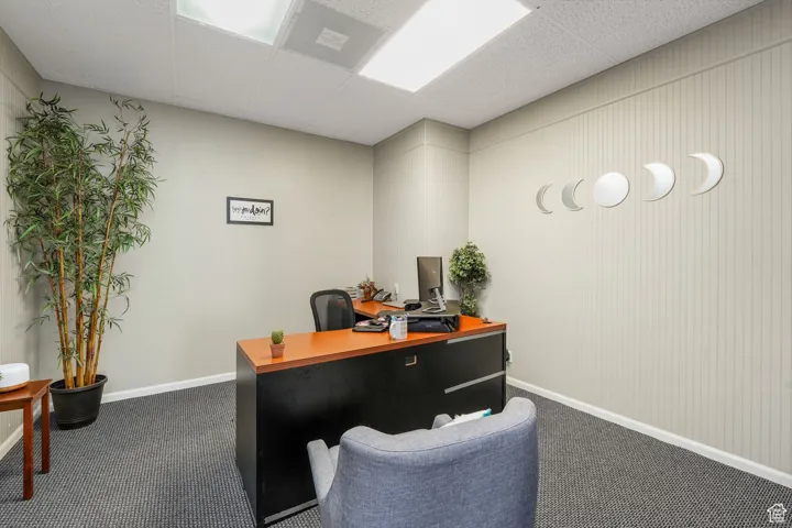 Home office with a drop ceiling and dark carpet