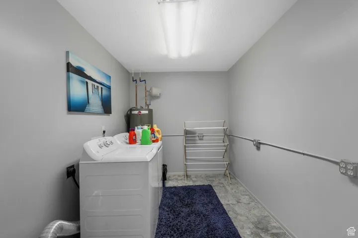 Washroom with a textured ceiling, independent washer and dryer, and water heater