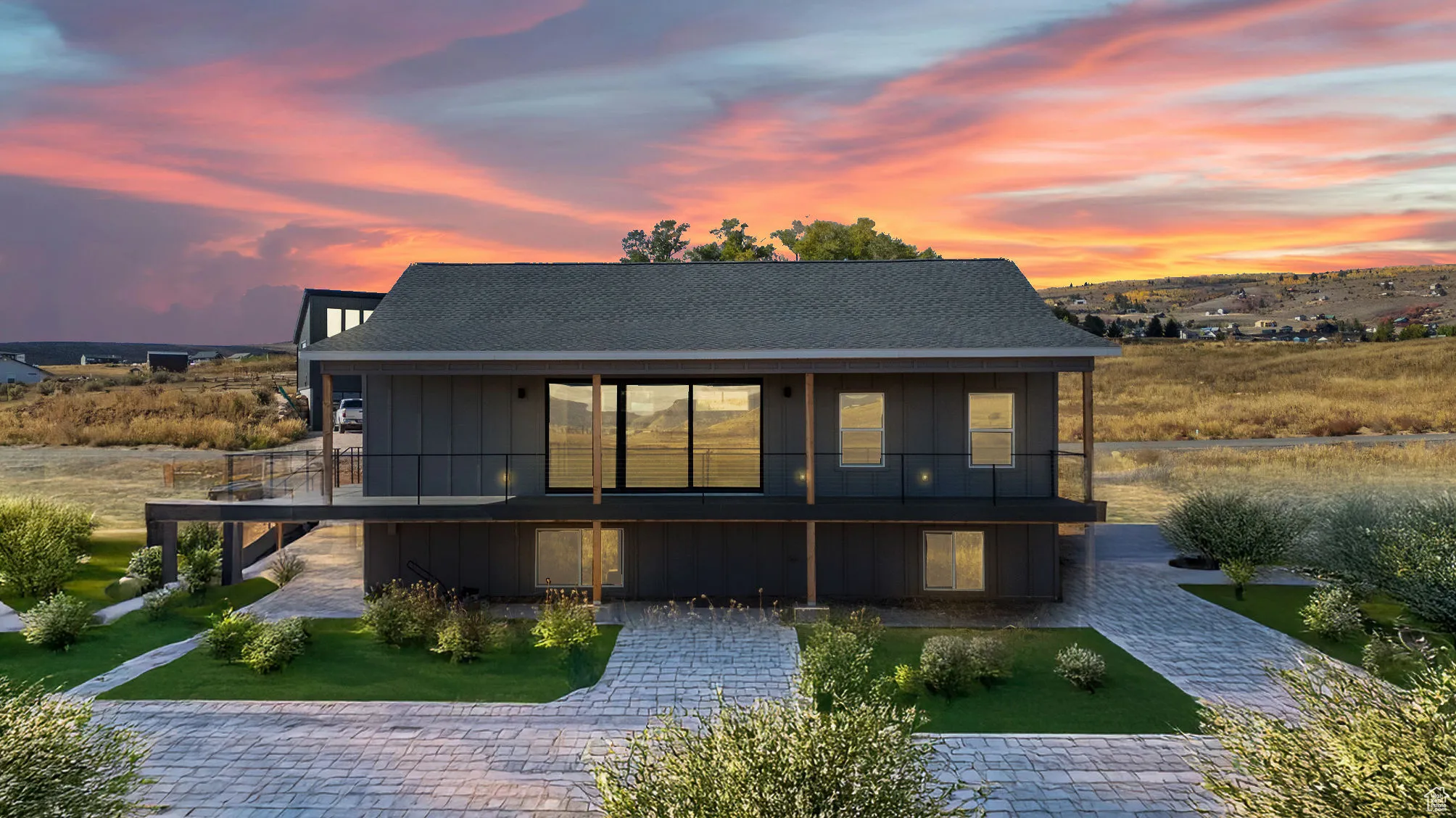 Rear view of house featuring roof with shingles, board and batten siding, a balcony, and a lawn/ landscape in this photo is virtual