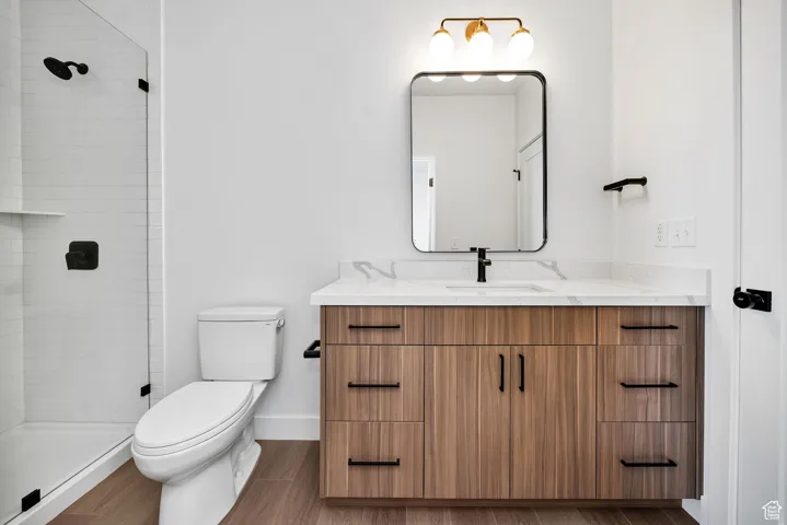 Full bath with vanity, a tile shower, and wood finished floors