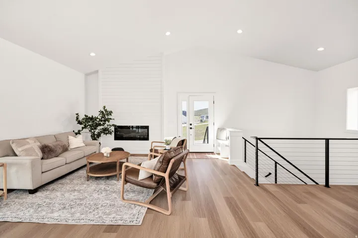 Living area featuring light wood finished floors, recessed lighting, a fireplace, and lofted ceiling