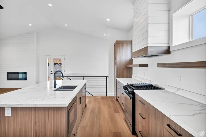 Kitchen featuring brown cabinets, open shelves, light stone counters, light wood-style floors, and recessed lighting