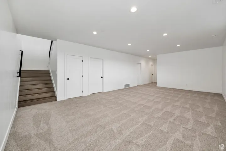 Basement featuring recessed lighting, light carpet, and stairs