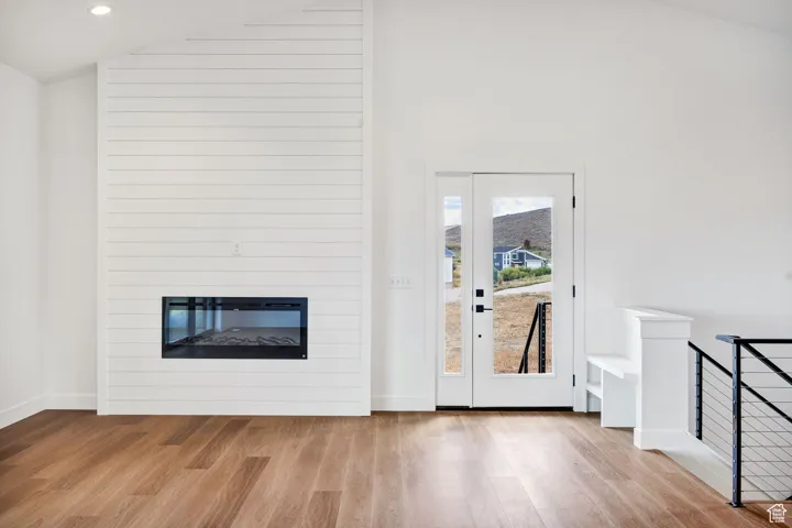 Entryway featuring a fireplace, wood finished floors, high vaulted ceiling, and recessed lighting