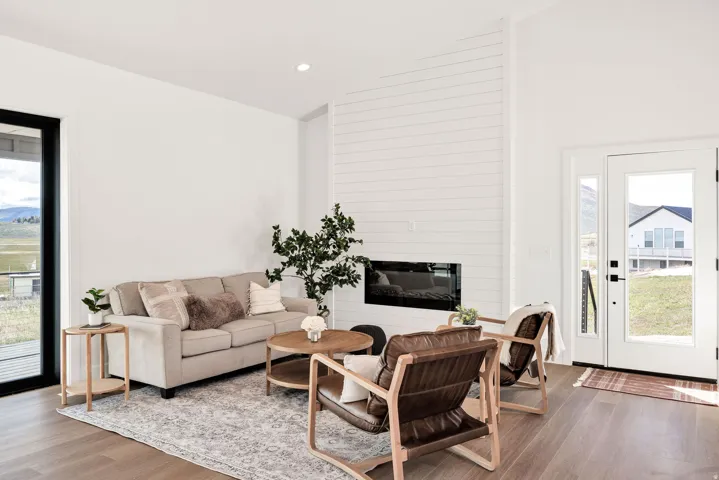 Living room with plenty of natural light, light wood finished floors, vaulted ceiling, a large fireplace, and recessed lighting