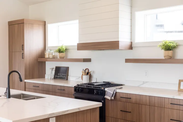 Kitchen featuring open shelves, modern cabinets, light stone counters, black gas range, and two tone cabinets