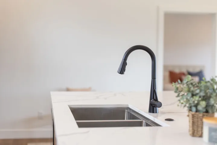 Kitchen view of light stone counters and a sink