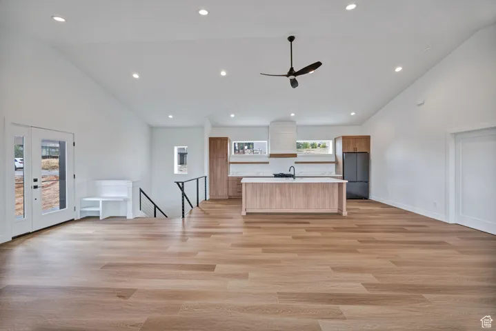 Kitchen featuring open floor plan, a center island with sink, light countertops, recessed lighting, and high vaulted ceiling