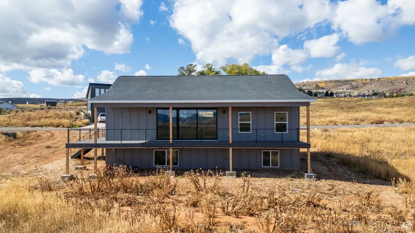 Rear view of house with a shingled roof and a wooden deck