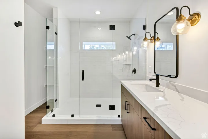 Full bathroom featuring vanity, dark wood-style flooring, a shower stall, and recessed lighting