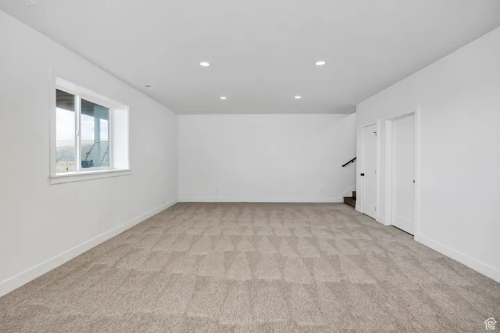 Spare room with light carpet, recessed lighting, and stairs