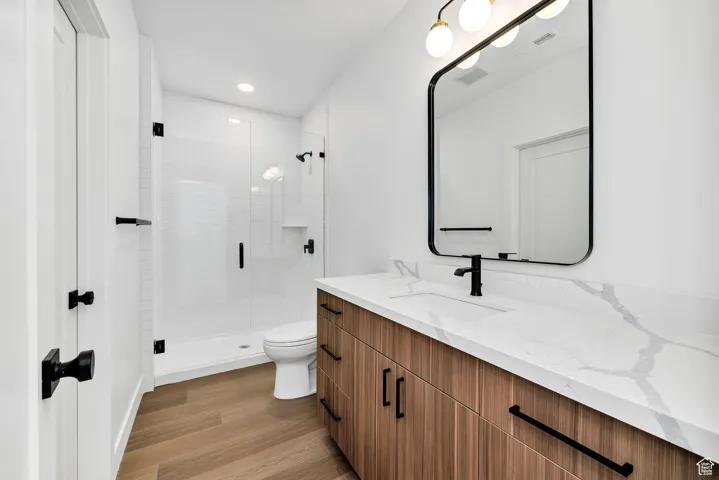 Bathroom with vanity, light wood-style floors, a stall shower, and recessed lighting
