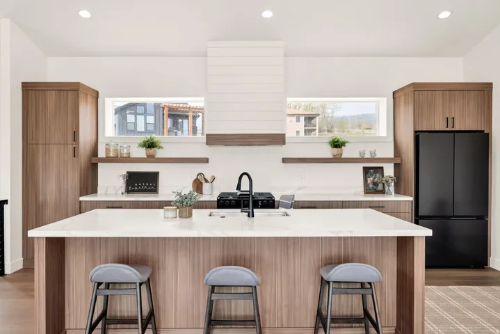 Two tone kitchen with freestanding refrigerator, light stone countertops, recessed lighting, light wood-style floors, and two tone color scheme