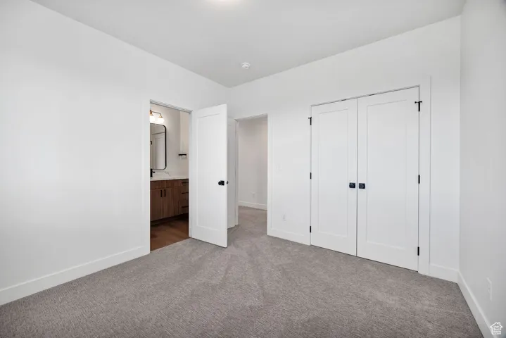Unfurnished bedroom with carpet, ensuite bathroom, and a closet