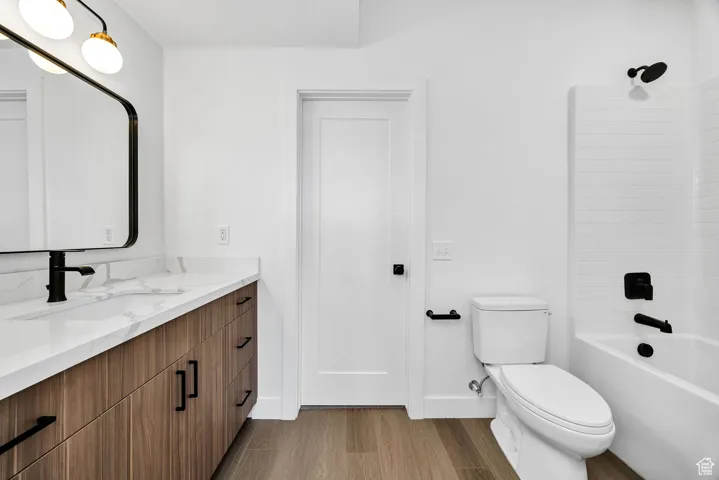 Bathroom with light wood finished floors, vanity, and washtub / shower combination