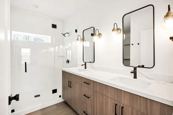 Full bathroom with double vanity, a stall shower, and light wood-type flooring