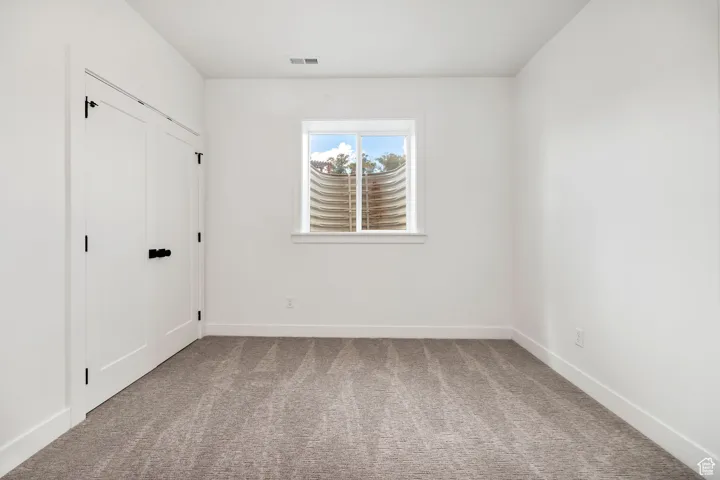Unfurnished bedroom featuring light carpet and a closet