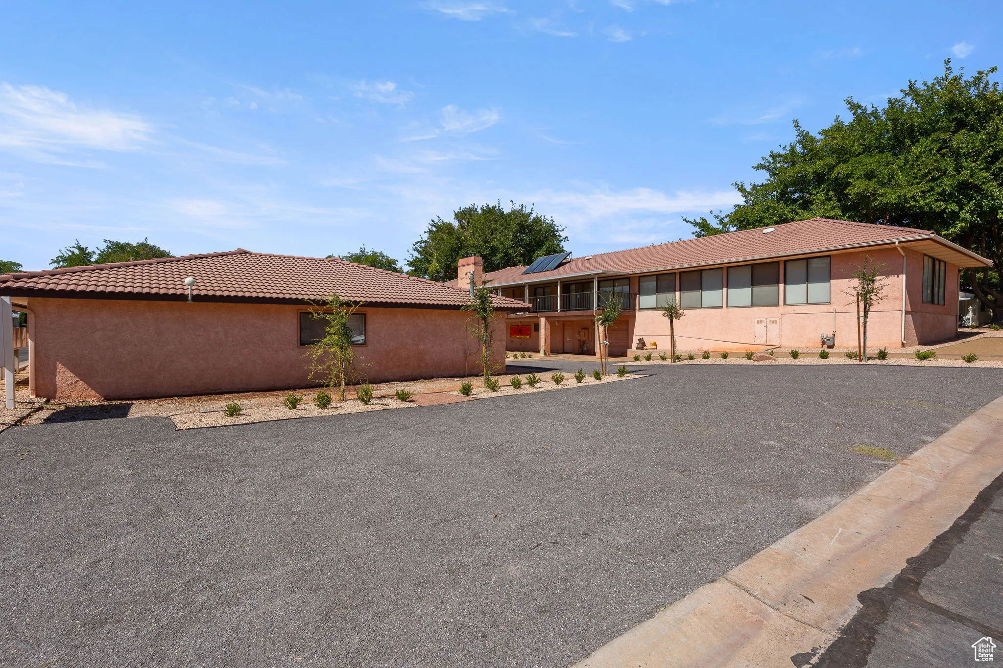 Single story home with a tile roof, solar panels, a chimney, and stucco siding