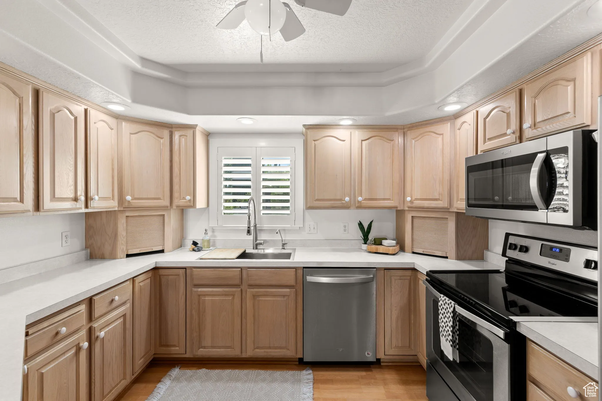 Kitchen with appliances with stainless steel finishes, light brown cabinetry, light countertops, and a textured ceiling