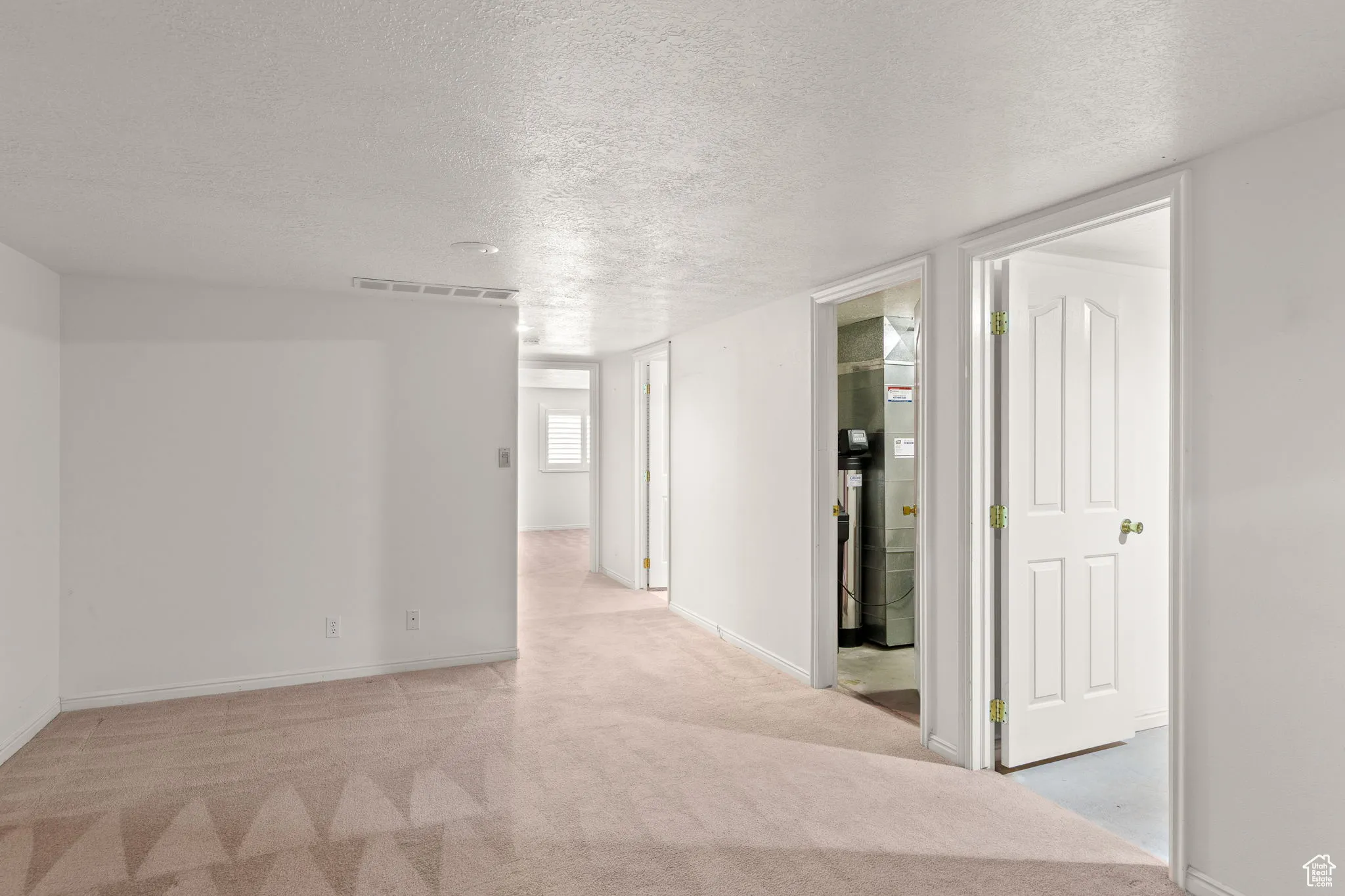 Hallway with a textured ceiling and light carpet