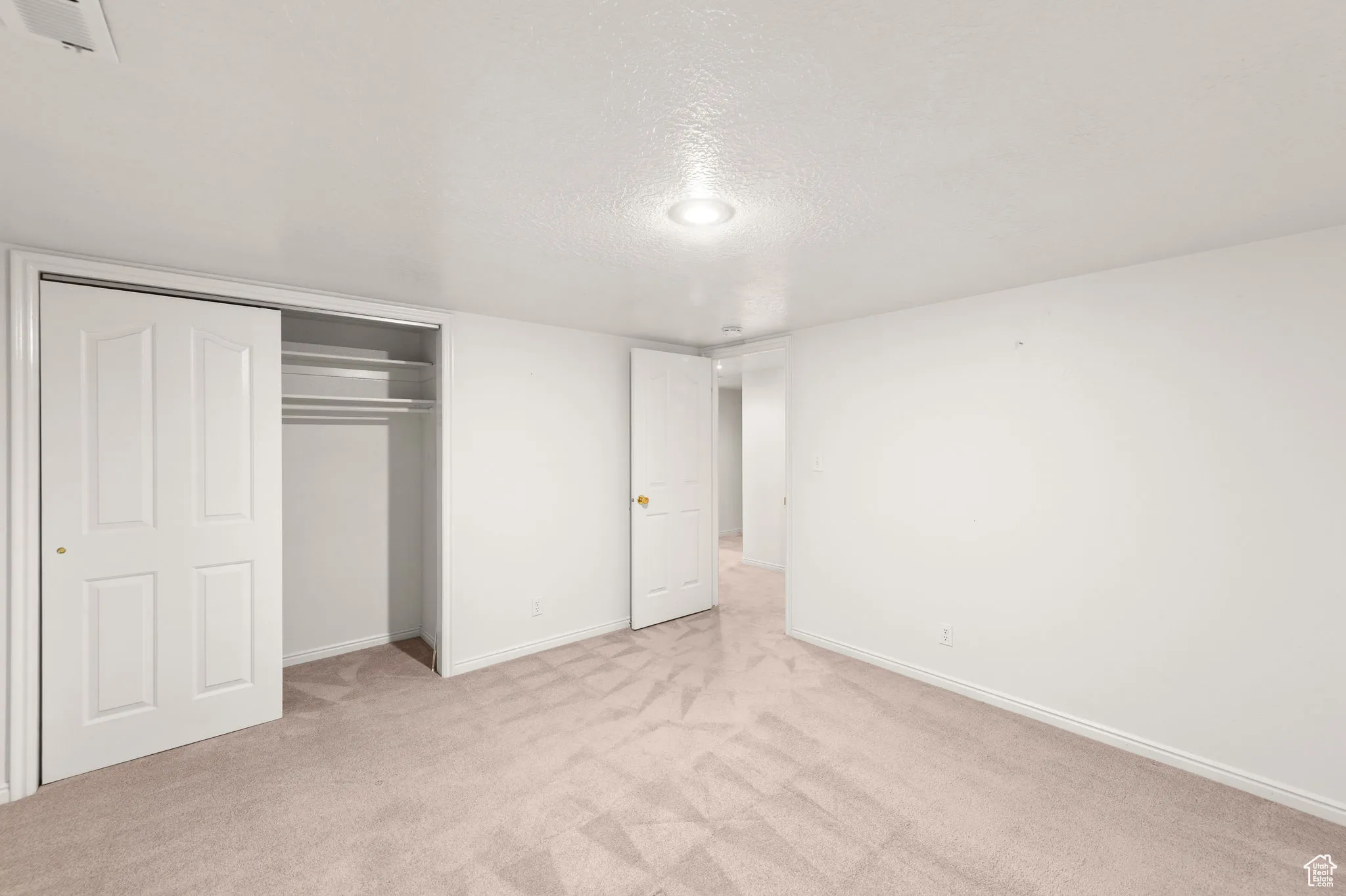 Unfurnished bedroom featuring carpet, a textured ceiling, and a closet