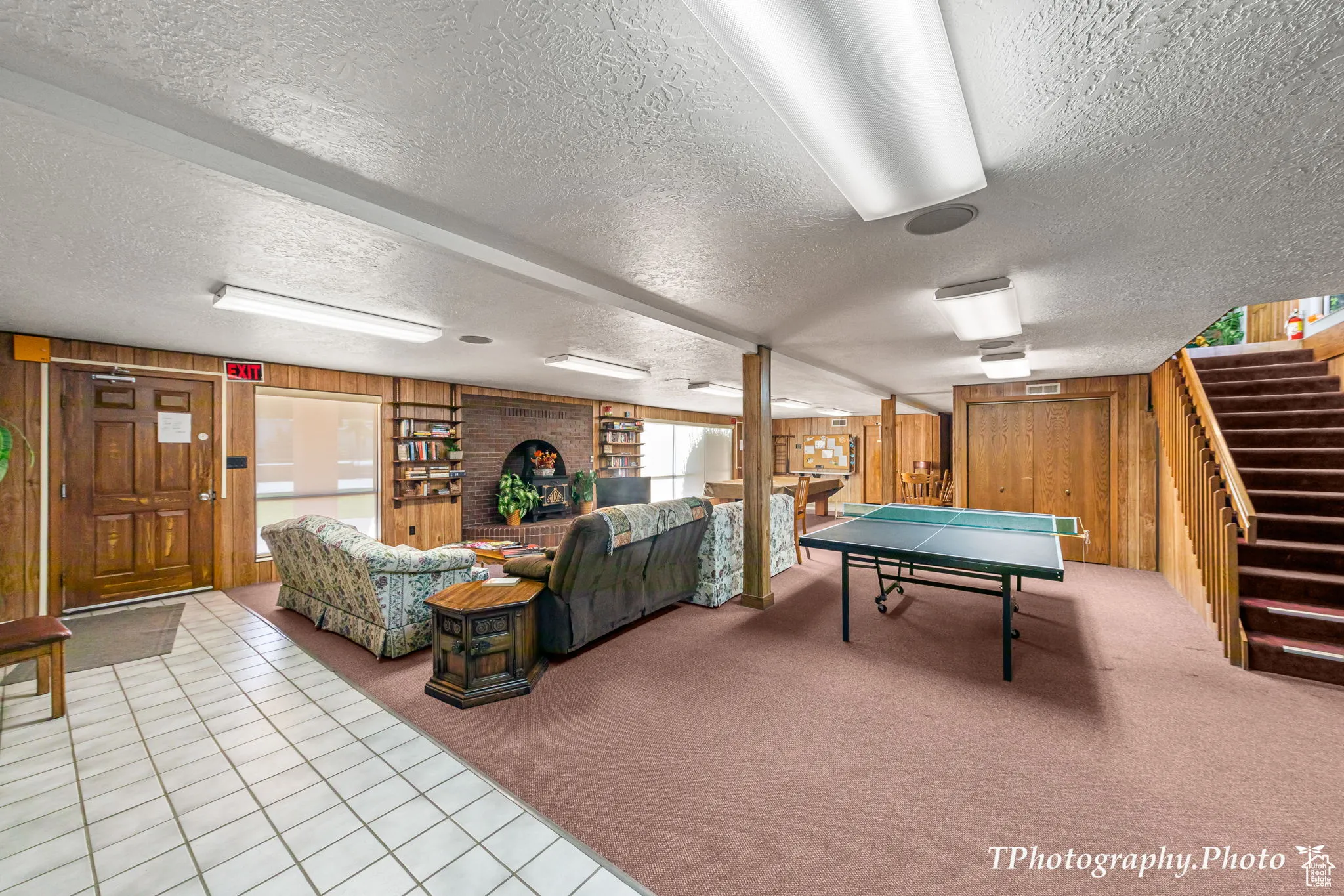 Game room with wood walls, carpet floors, a textured ceiling, and tile patterned floors