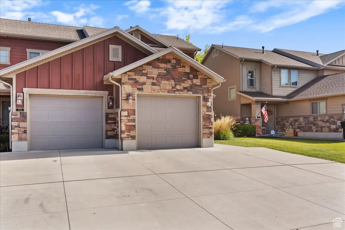 Craftsman-style house featuring board and batten siding, concrete driveway, stone siding, and a garage