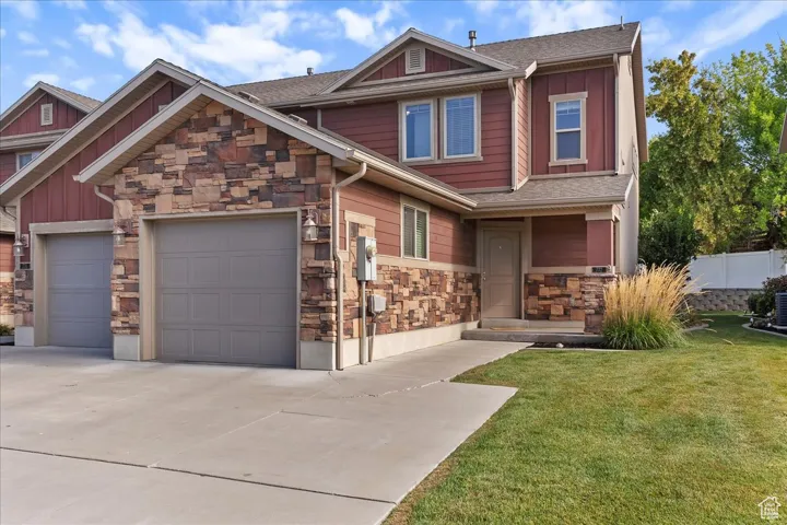 Craftsman-style home with driveway, roof with shingles, stone siding, and a garage